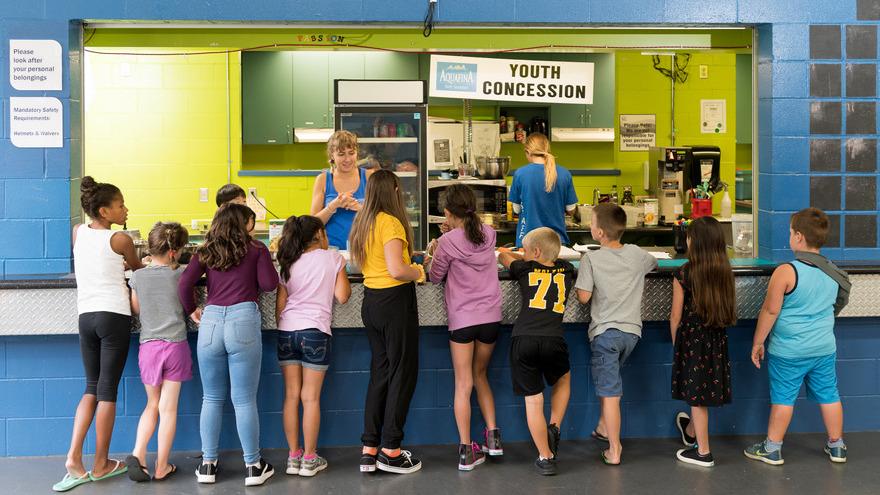 Two staff members take orders at the Greg Moore Youth Centre concession from a lineup of children.