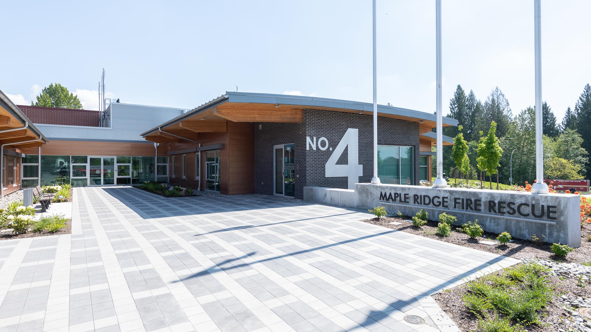 A large white number 4 is proclaimed on the black brick wall of Fire Hall number 4 along a brickwork path into the building.