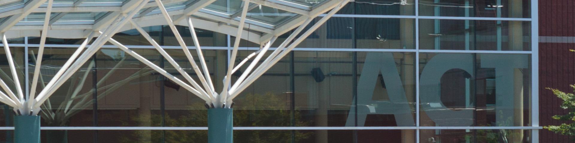 Large beams support an overhead awning next to the glass panels of the ACT Arts Centre's front facade.