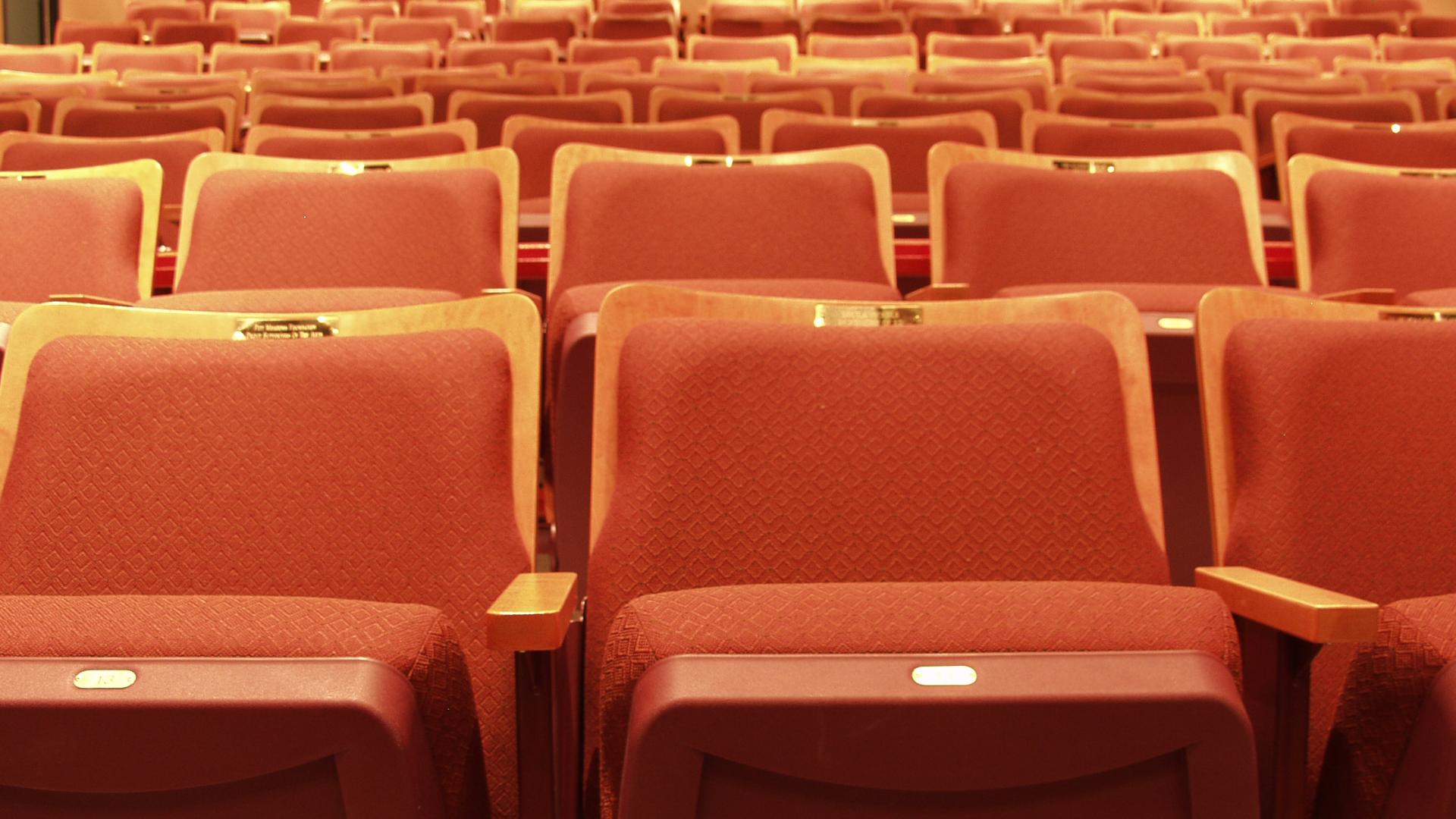 A sea of empty red chairs waiting to be filled faces the main stage of the ACT Arts Centre.