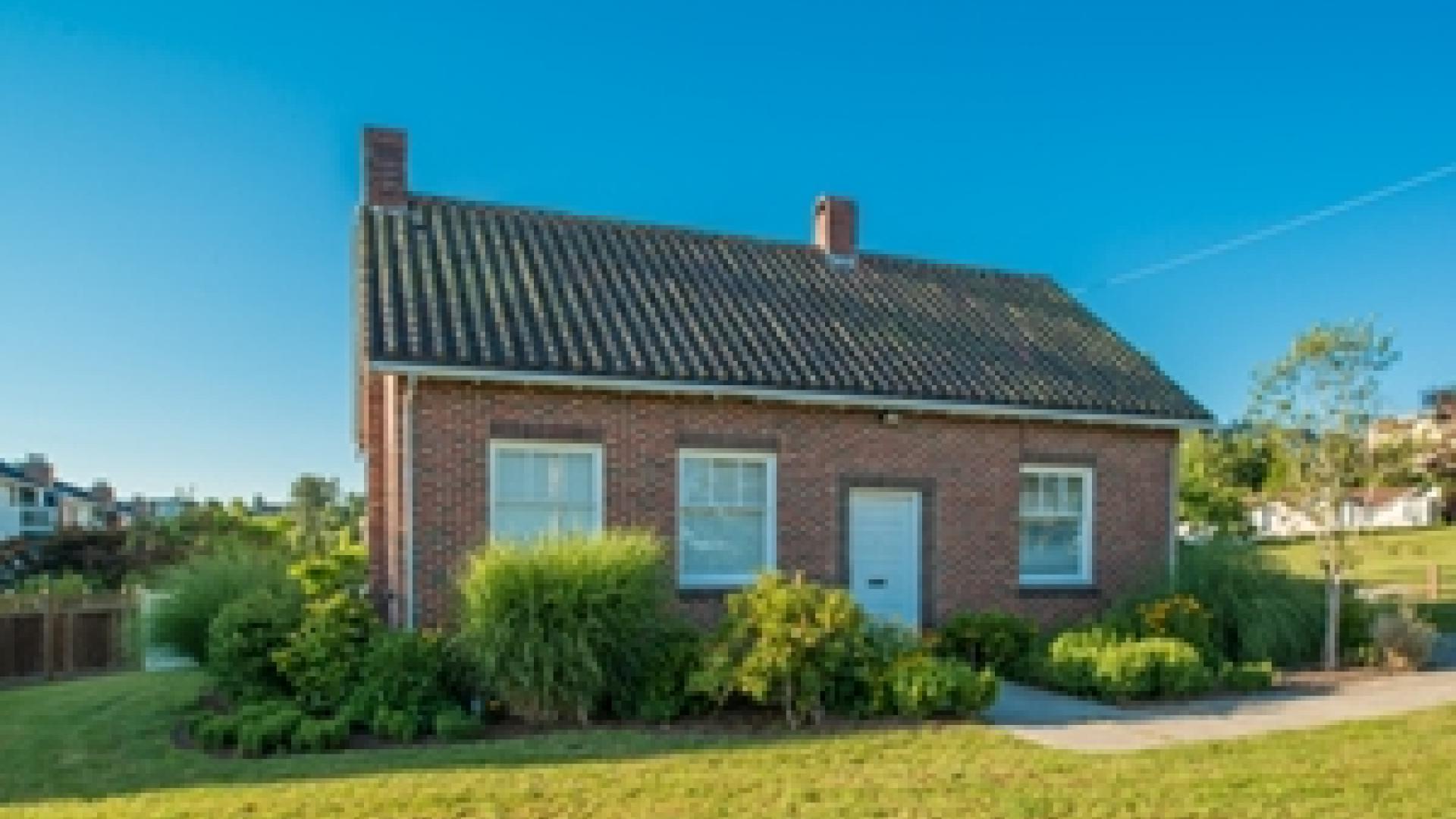 Exterior of Brickyard office. There is a small brick building surrounded by shrubs.