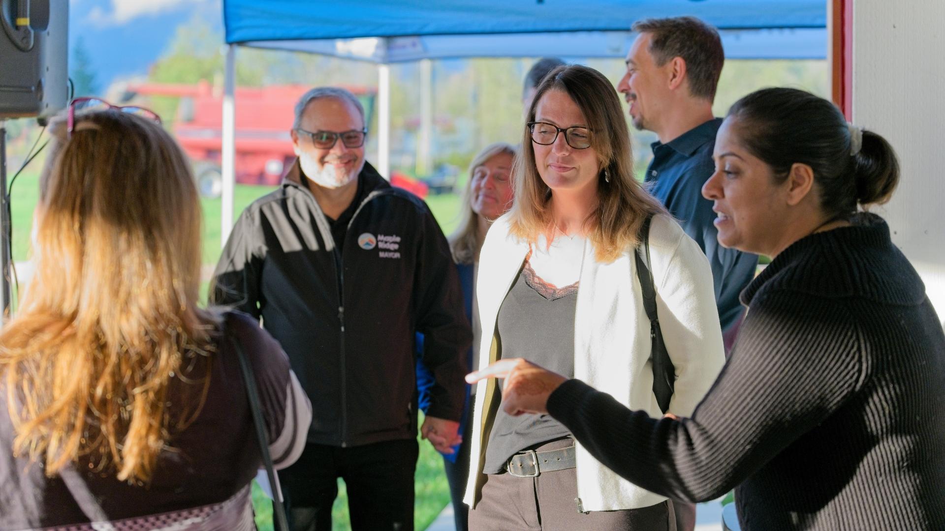 A woman points out an object off-screen to two other women she's speaking to at the Innovation Challenge Awards Event.