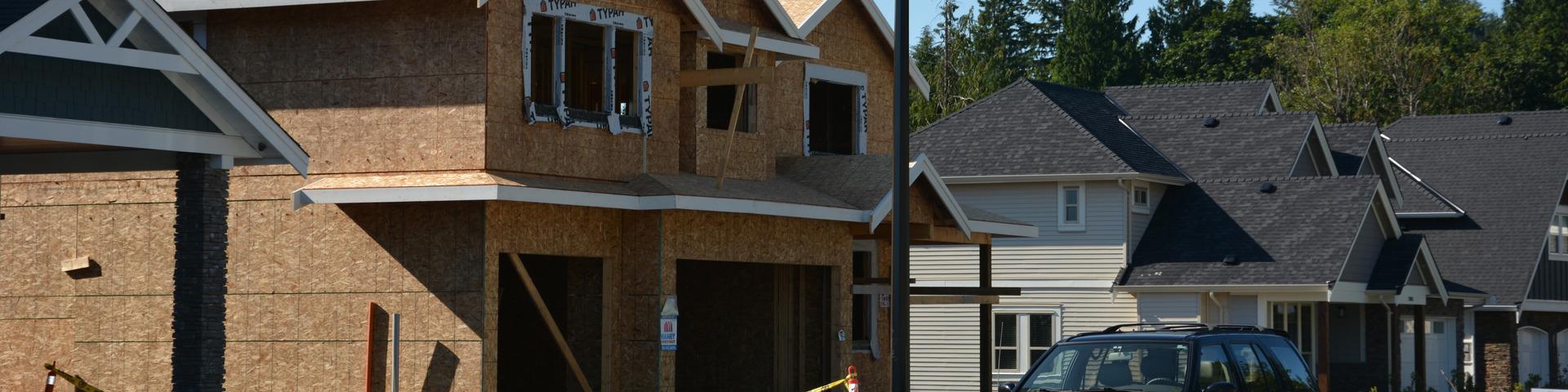 A house mid-construction sits next to a completed home on its street.