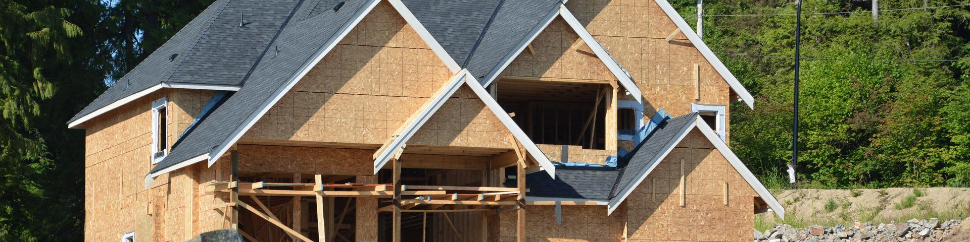 A partially constructed house sits against the backdrop of a forest.