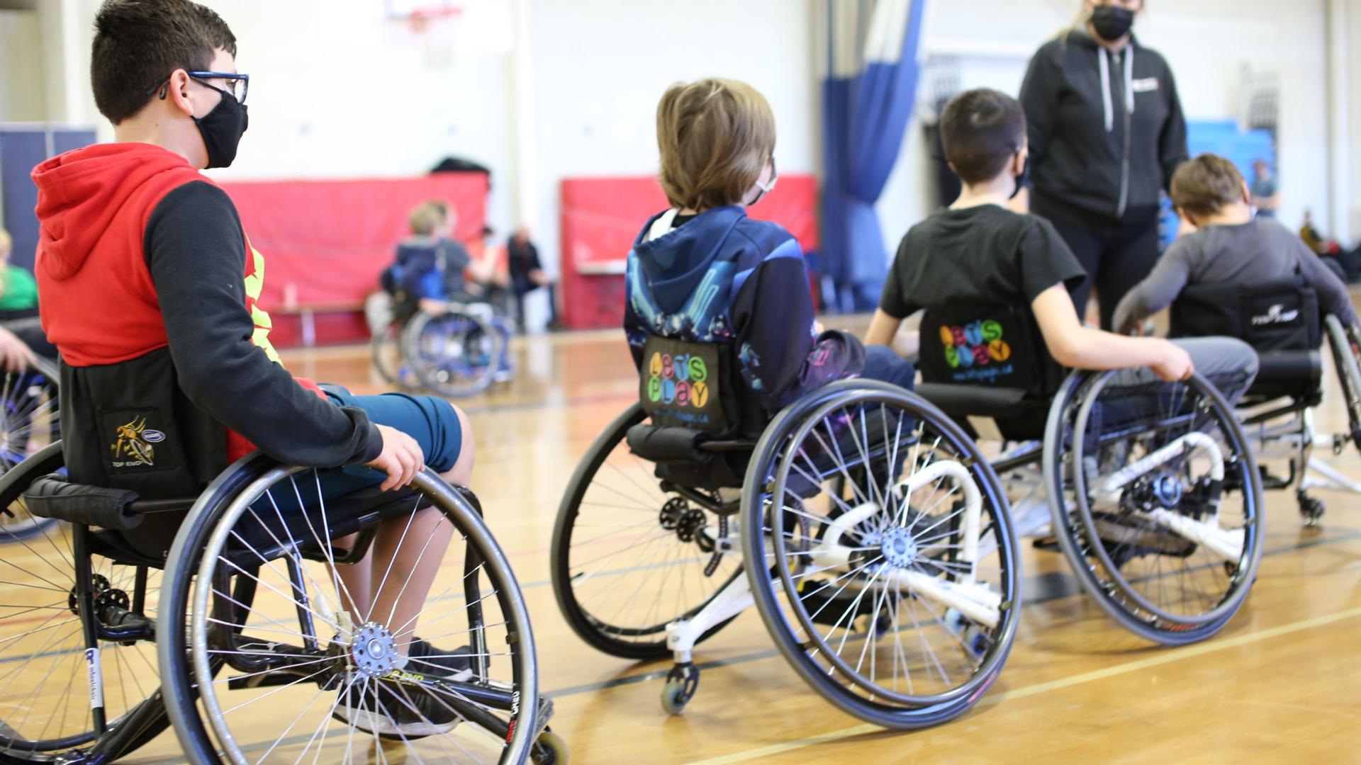 Four young kids in wheelchairs on a gymnasium court