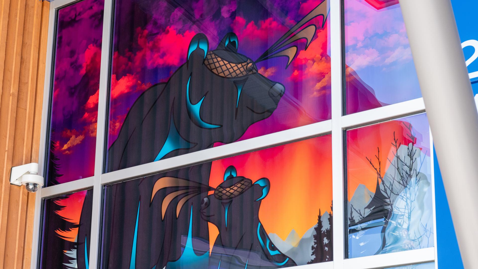 An image-based window covering depicting a mother bear and her cub being silhouetted by the sunset rests on display at the Albion Community Centre.