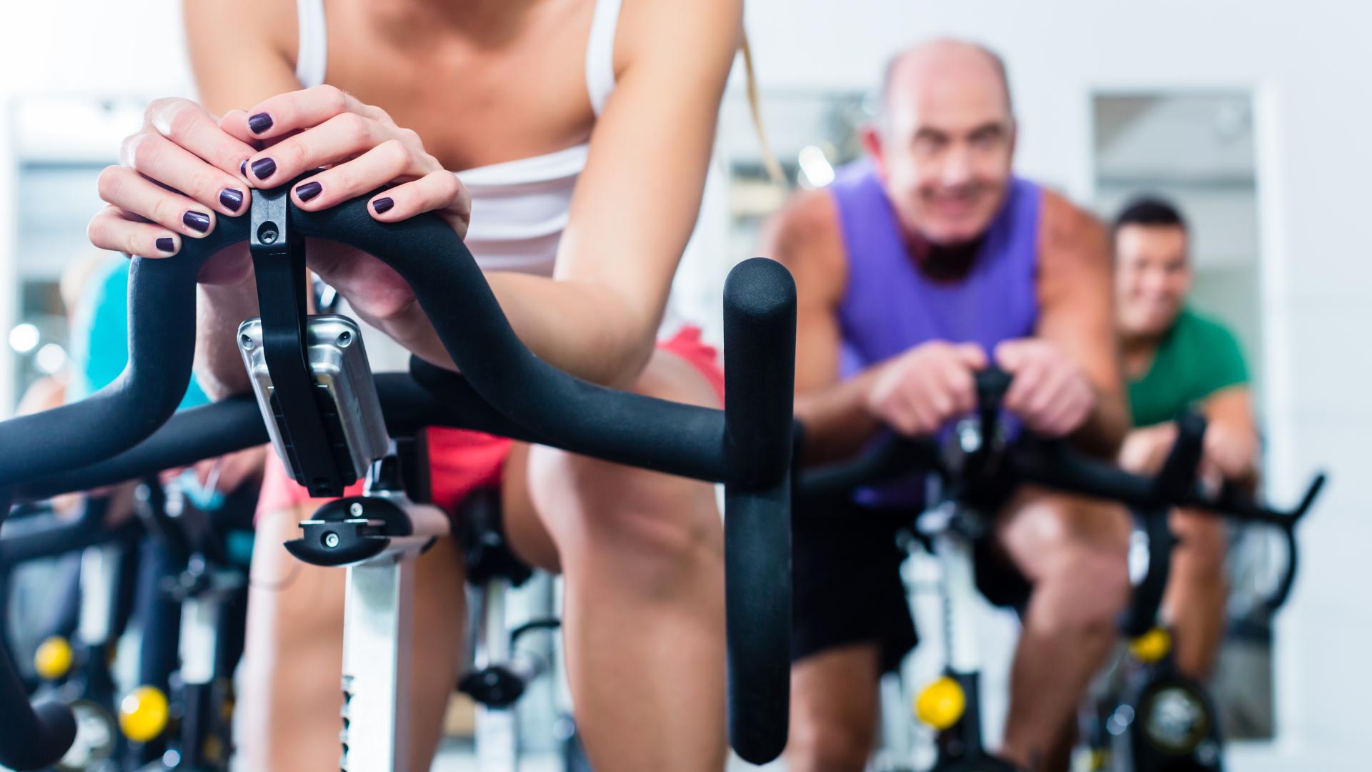 A group of people exercise on stationary bicycles.