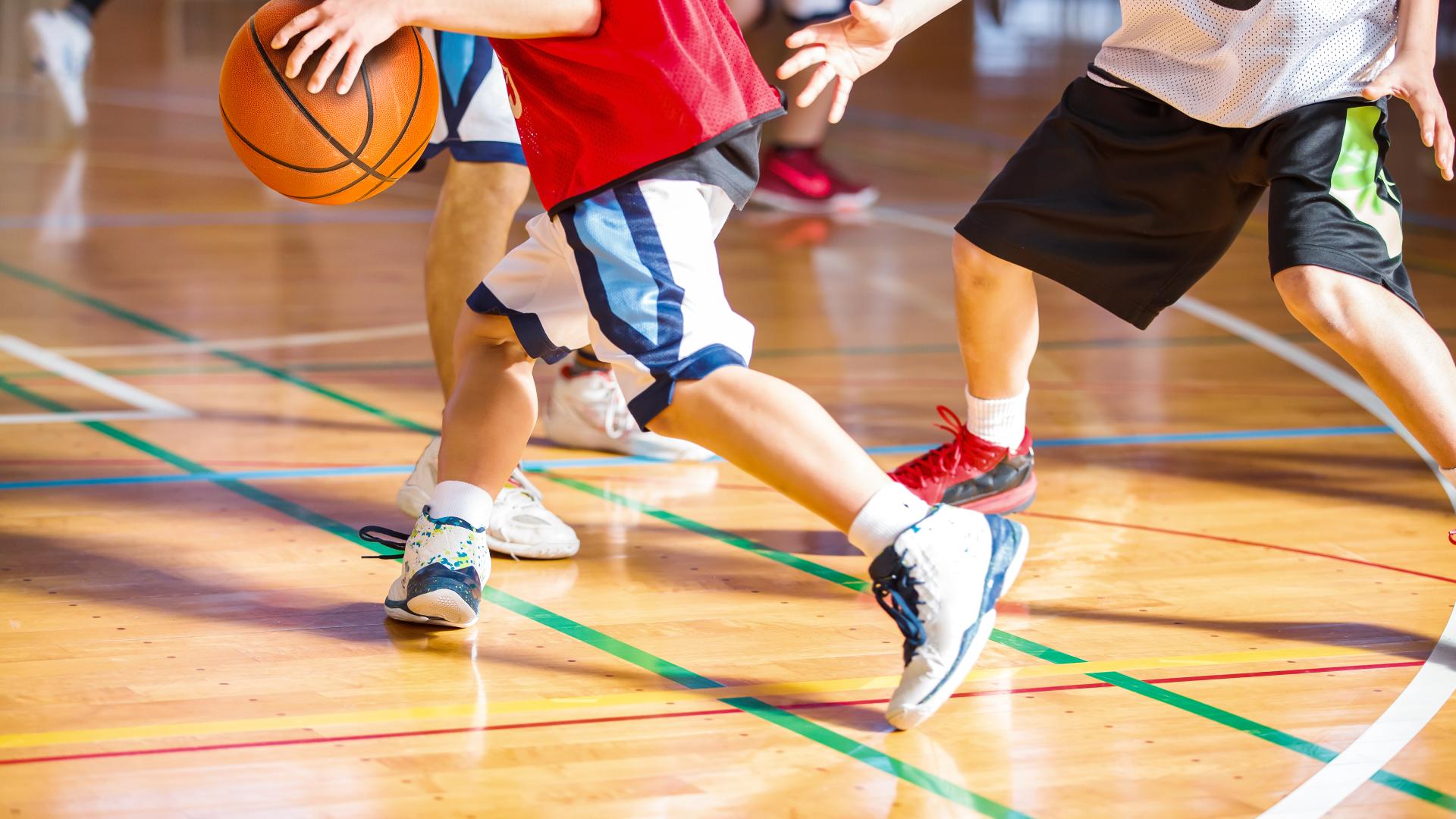 A group of people play basketball on an indoor court.