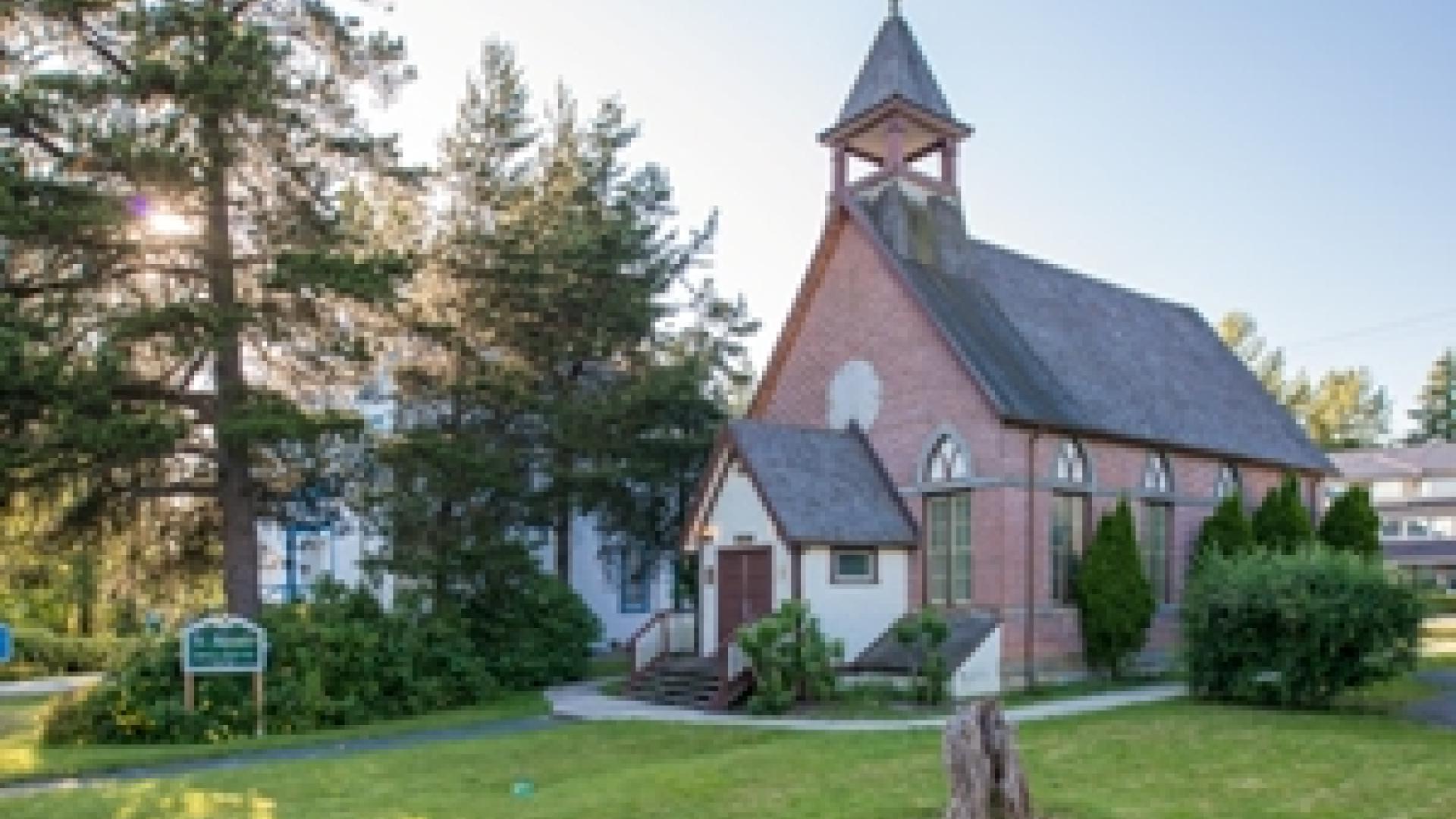 Exterior of St. Andrew's Heritage Church. The church is a small brick building with two large wooden doors at the front.