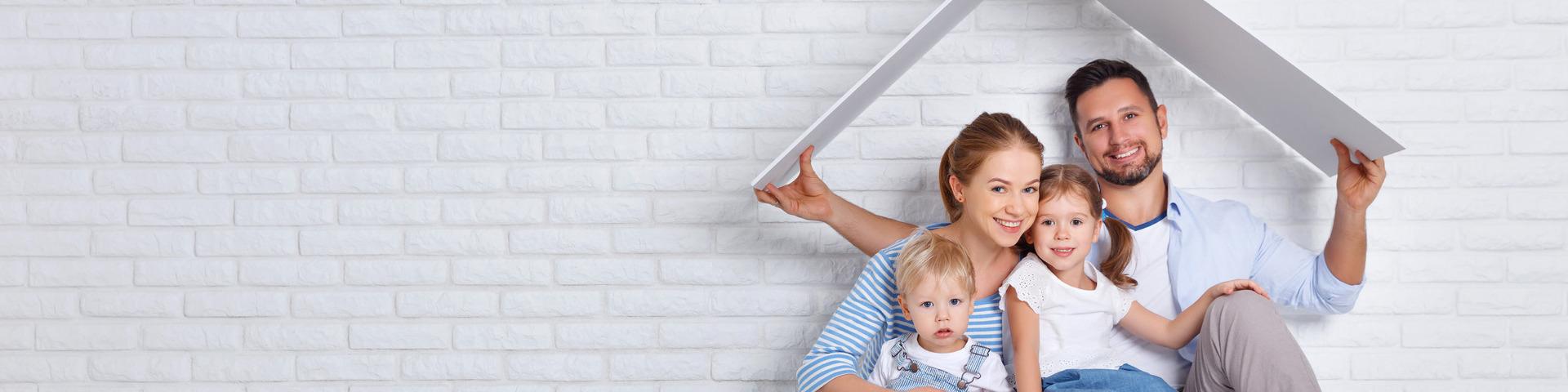 A family sits under a cut out piece of paper resembling a stylized house roof.