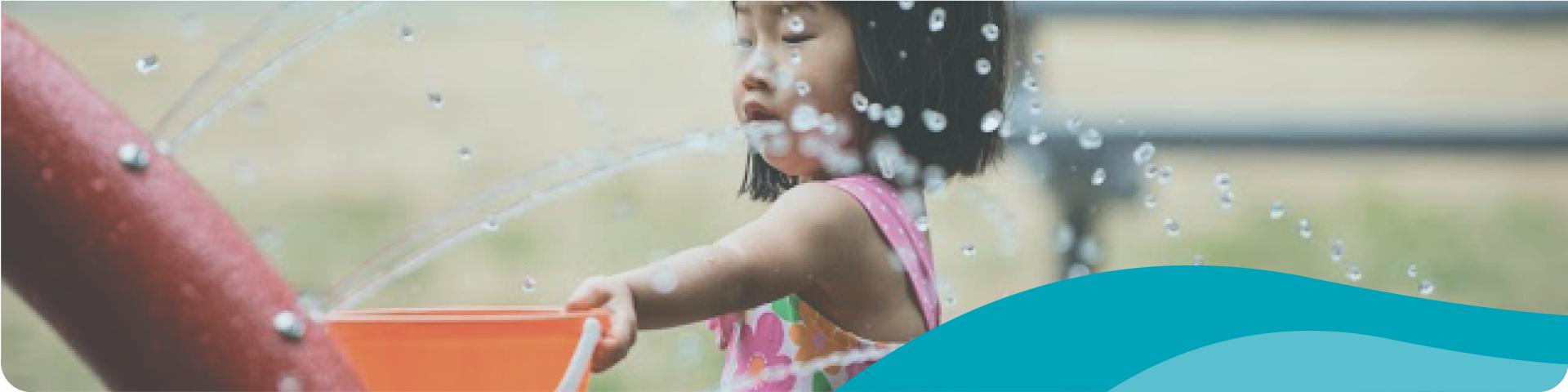 little girl with a bucket at a spray park