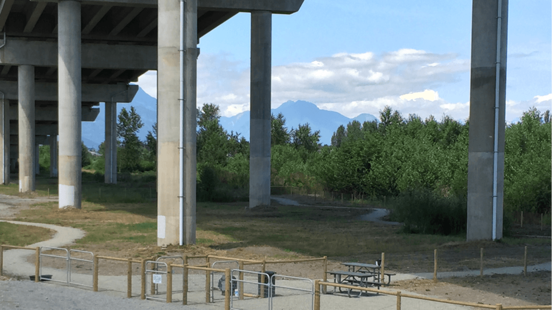 Entrance to park. There is some railing at the entrance. The park is under an overpass.