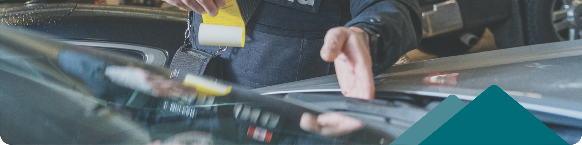 bylaw officer putting ticket under car wiper